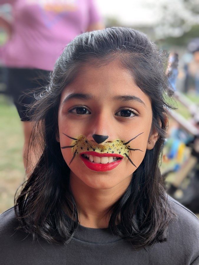 Smiling child with a golden leopard nose and whiskers face painting
