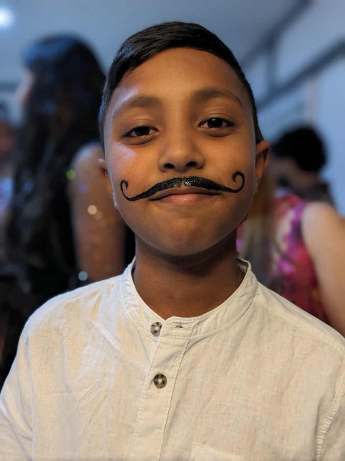 Smiling child with a painted curly black moustache