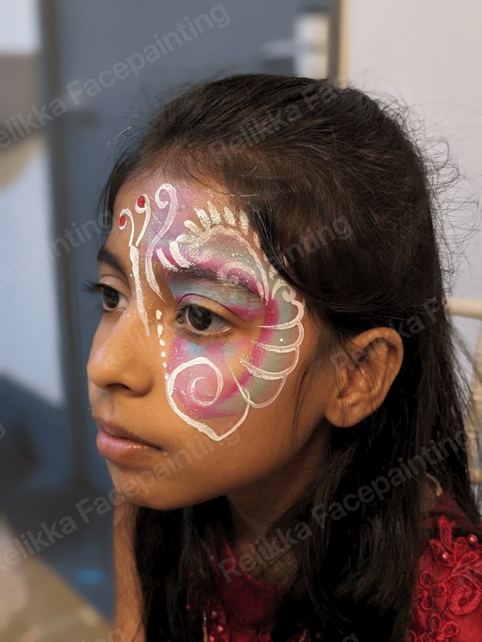 Child with a pink and white swirling filigree face painting